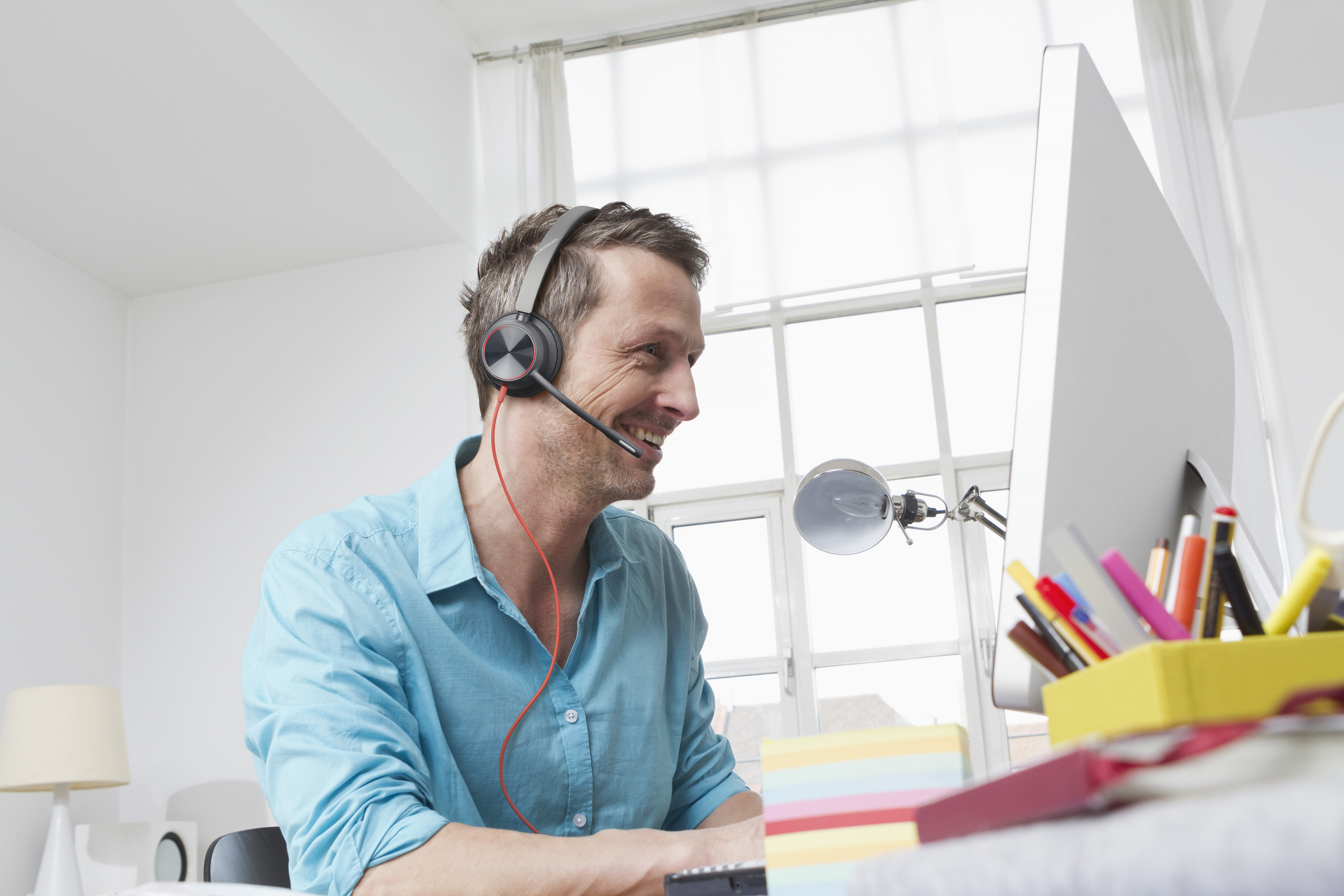 Man at home wearing a blackwire 8225 headset sitting at computer